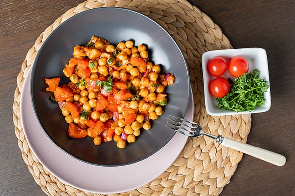 Angharad_Evans_Body_Talk-1110 Food photography Chick pea recipe in a grey bowl on a white plate on a woven placemat with a square bowl of tomatoes to the side, for a product photosession in Penarth cardiff