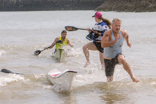 Participants at Beachfest Porthcawl paddle together in the water, creating a lively scene of fun and teamwork