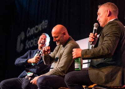 Sean Holley, Lawrence Dallaglio OBE and Neil Back MBE laughing on a stage