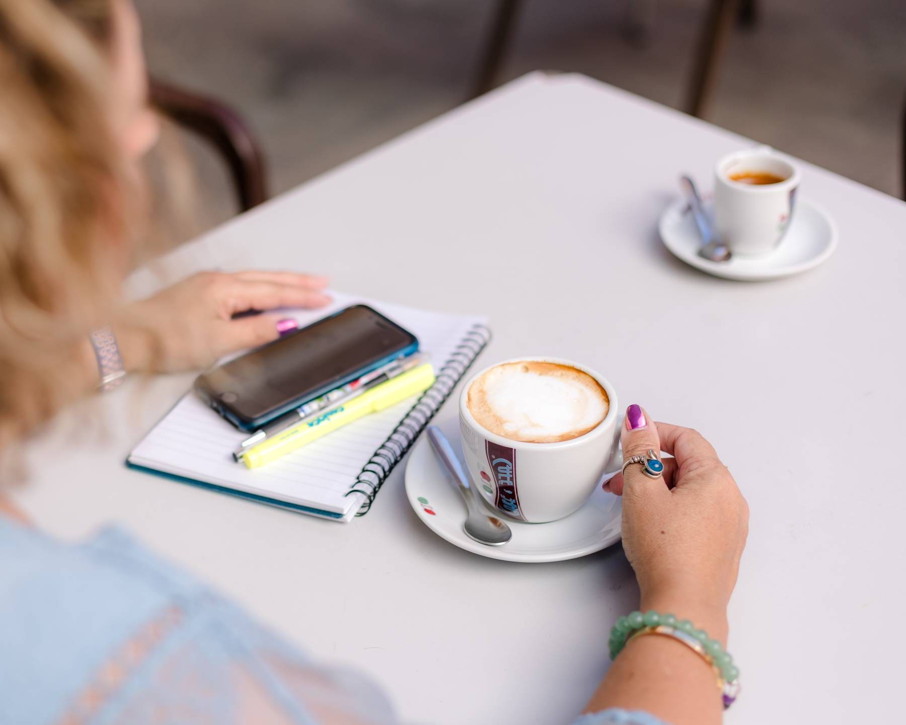 Returning to Gran Canaria, looking over the shoulder of a person at a cafe table, she is holding the handle of a coffee cup